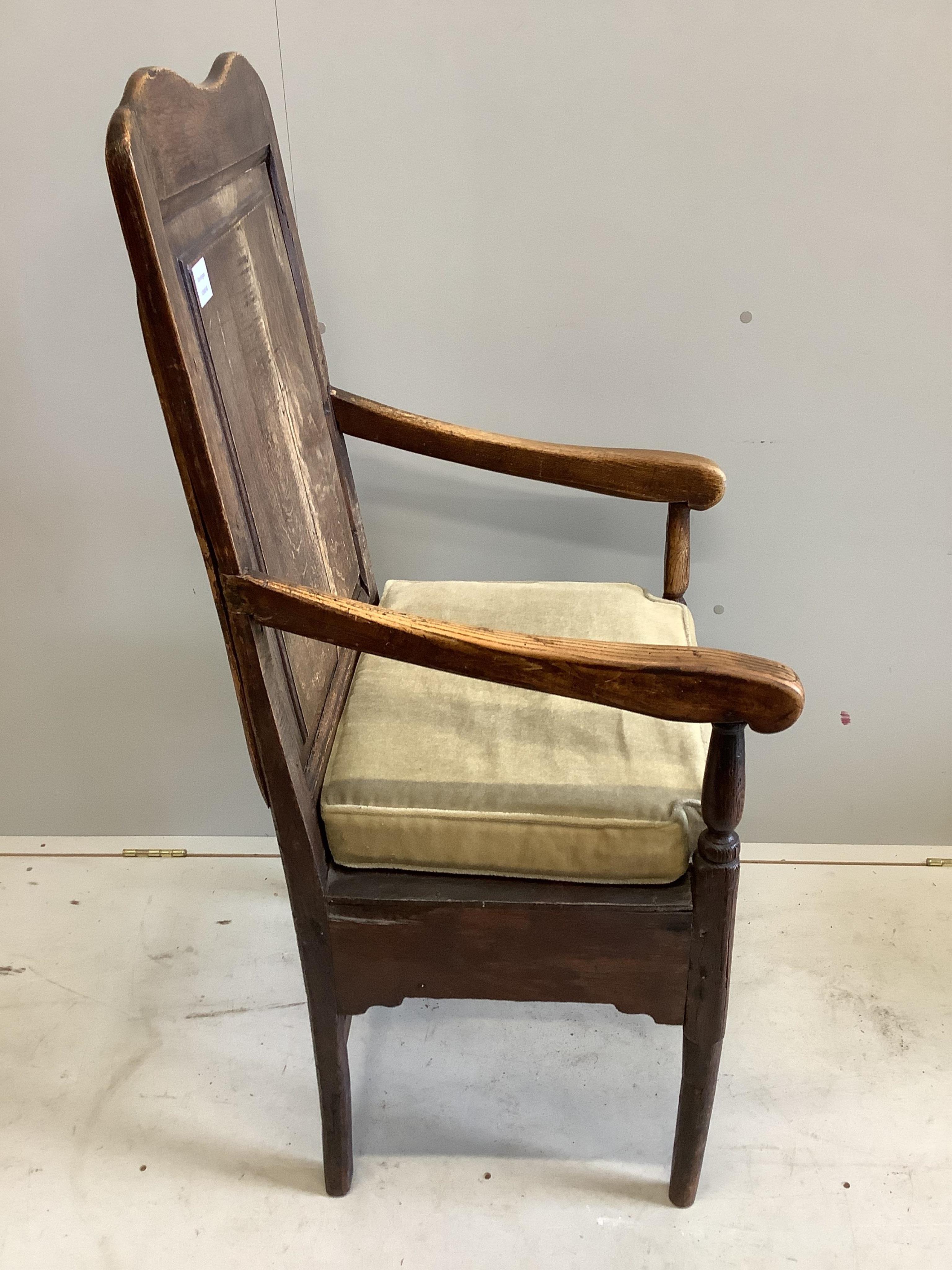 An early 18th century oak panel back open armchair, width 56cm, height 123cm. Condition - faded and worn with a missing drawer beneath the seat